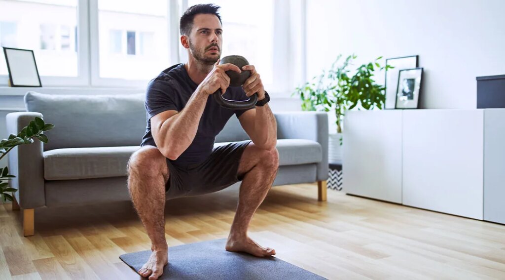 Man over 40 working out at home with a kettlebell squat.jpg