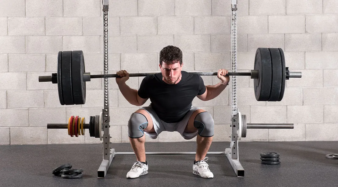 Athletic young man performing a deep squat depth to build his glute and leg muscles.jpg