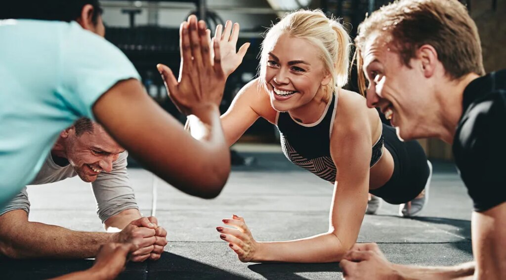 Young fit athletic group high fiving each other while performing planks.jpg