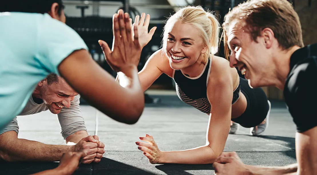 Young fit athletic group high fiving each other while performing planks.jpg